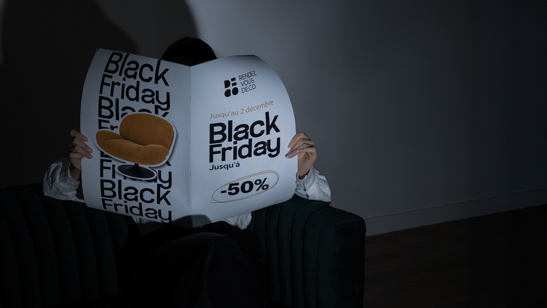 Visuel Black Friday Rendez Vous Déco : derniers jours jusqu’au 2 décembre, -50 %, personne assise dans un fauteuil lisant un grand catalogue avec un fauteuil orange mis en avant.