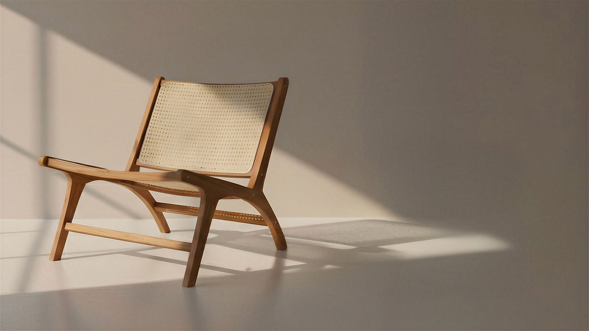 Fauteuil lounge en bois naturel avec dossier en cannage, design épuré et chaleureux, mis en scène dans un intérieur minimaliste avec lumière naturelle et jeux d’ombres