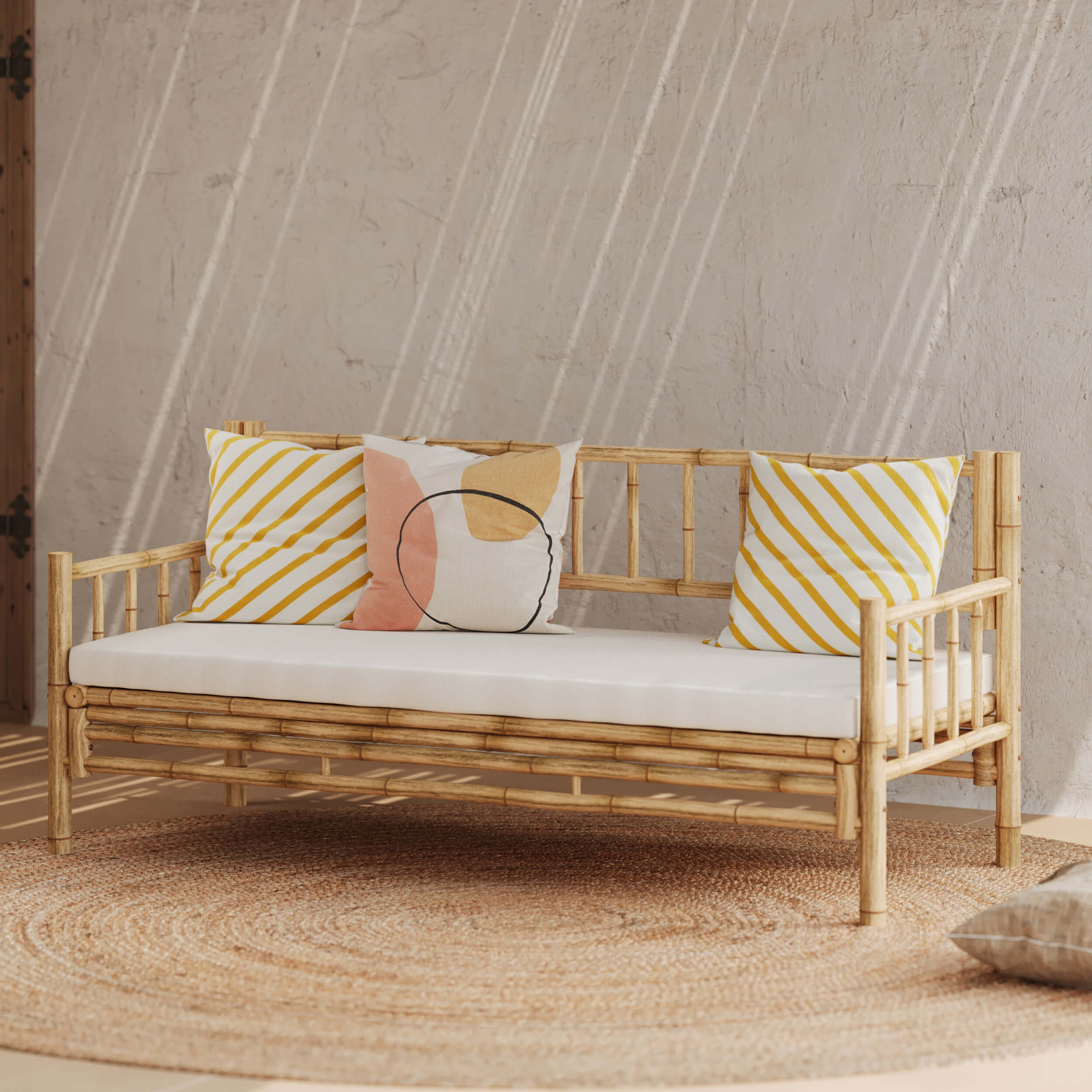 Canapé en bambou avec assise blanche et coussins décoratifs jaunes et motif abstrait, ambiance naturelle et lumineuse, mur texturé et tapis rond en fibres naturelles, Rendez-vous Déco