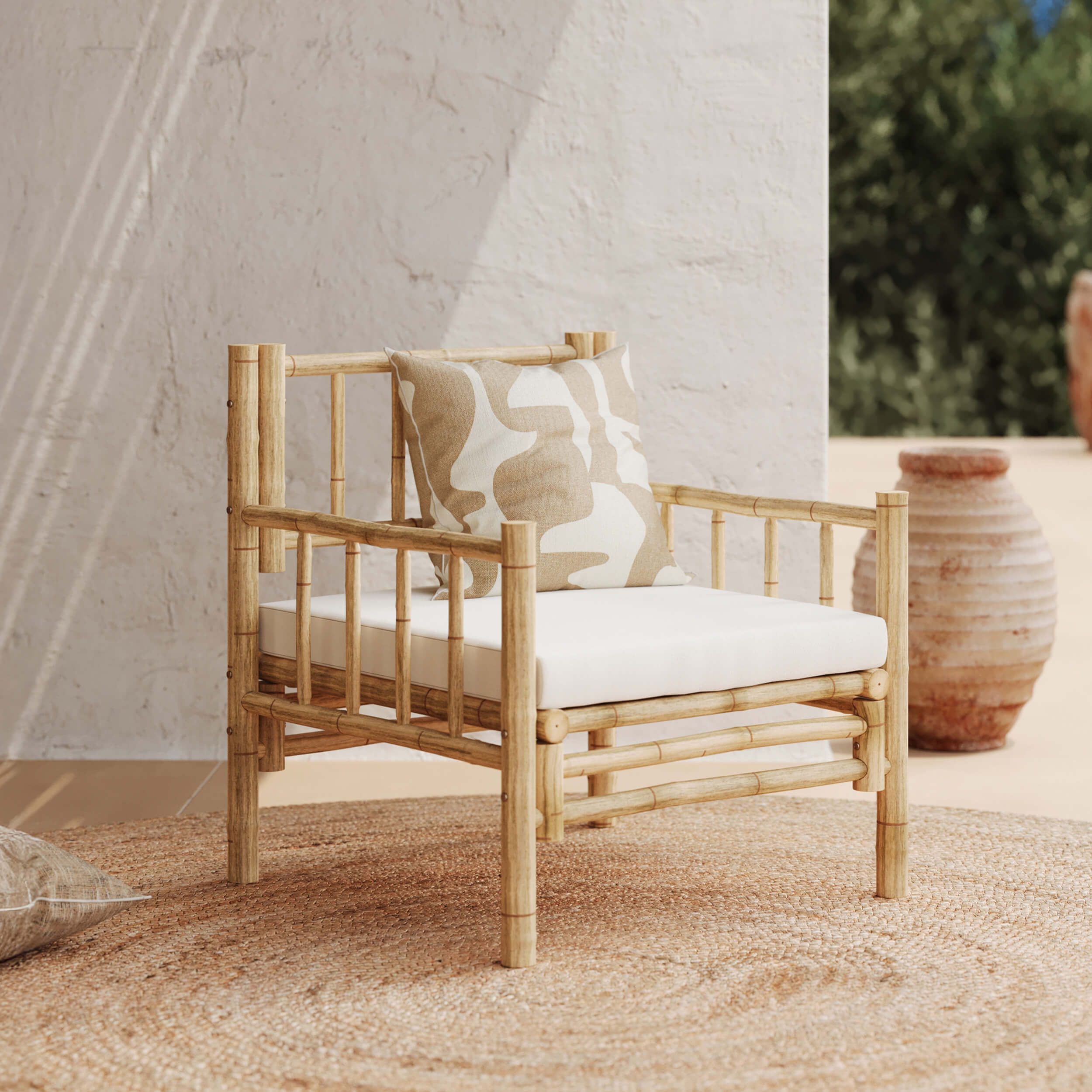 Fauteuil en bambou avec coussin d’assise blanc et coussin décoratif beige à motif abstrait, posé sur un tapis rond en fibres naturelles, ambiance chaleureuse et lumineuse, Rendez-vous Déco