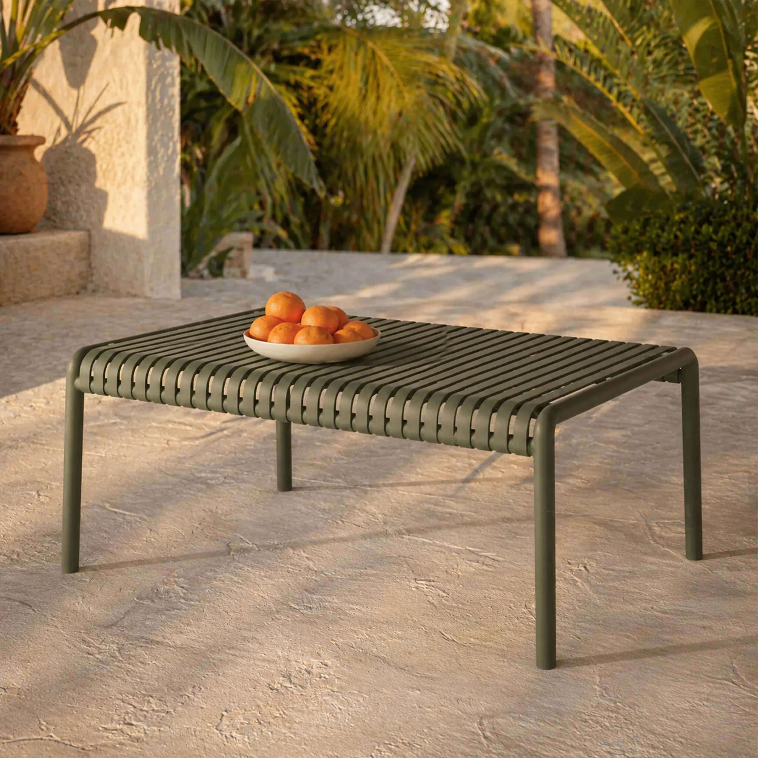 Table basse de jardin en métal à lattes vert olive, style moderne sur terrasse ensoleillée avec végétation tropicale – Rendez-vous Déco