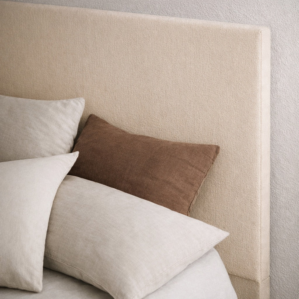 Tête de lit rembourrée en tissu beige à la texture douce, accompagnée de coussins en tons neutres, style contemporain et minimaliste, ambiance chaleureuse et apaisante, Rendez-vous Déco
